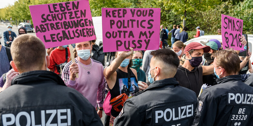 Demonstrant:innen mit Schildern und Polizisten