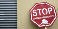 Ein Pappschild "Stop Zwangsräumungen" lehnt an einer Wand