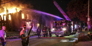 unter Polizeischutz löscht die Feuerwehr einen Gebäudebrand in St. Louis