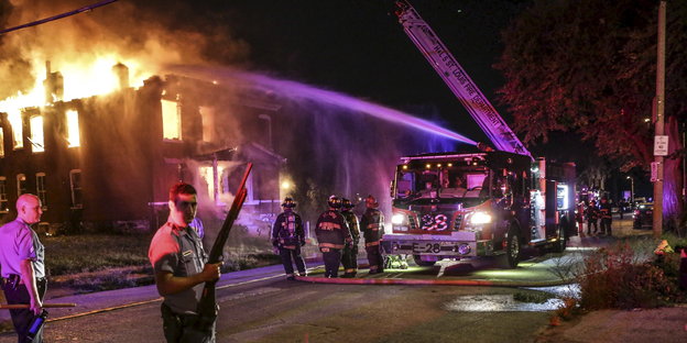 unter Polizeischutz löscht die Feuerwehr einen Gebäudebrand in St. Louis