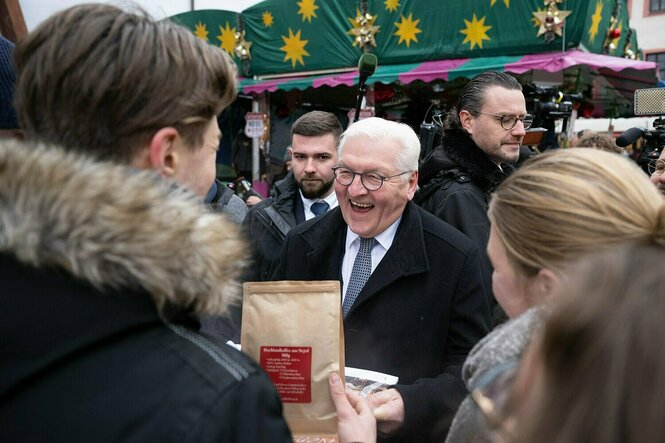 Frank Walter Steinmeier spricht auf einem Weihnachtsmarkt mit menschen