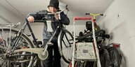 Mann mit Mütze hebt Fahrrad in einer Garage hoch