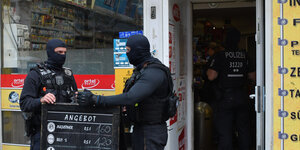 zwei Polizisten stehen vor einem Geschäft in Neukölln bei einem Verbundeinsatz zur Gewerbekontrolle