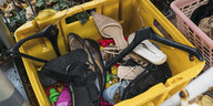 Gebrauchte Schuhe und andere Dinge liegen in einer gelben Kiste
