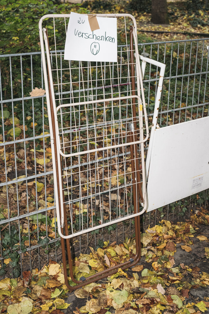 ein rostiger Wäscheständer lehnt an einem Zaun