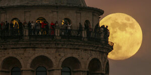 Ein Mond an einem Turm voller Menschen