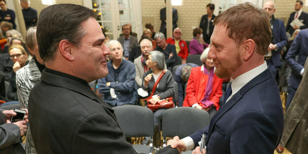Author Uwe Tellkamp and the Saxon Prime Minister Michael Kretschmer shake hands