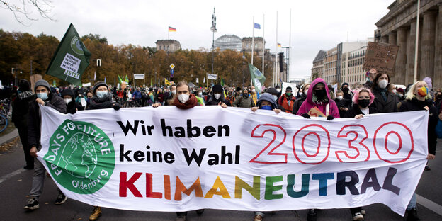 Menschen demonstrieren hinter einem transparent für mehr Klimaschutz