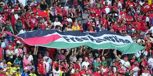 Fans in Katar halten eine palästinensische Flagge mit der Forderung Free Palestine