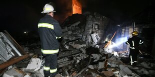 Feuerwehrleute vor zerstörtem Gebäude