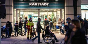 Mehrere Menschen vor dem beleuchteten Eingang der Karstadt-Filiale