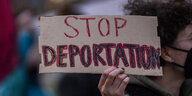 Ein Demonstrant hält ein Schild hoch mit der Aufschrift "Stop Deportation"
