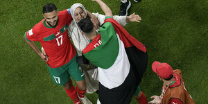 Marokkanische Spieler feiern mit Bakannten, ein Spieler ist eikne Palestinafahne gehüllt