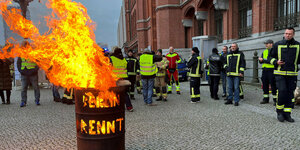 Das Foto zeigt protestierende Feuerwehrleute hinter einem brennenden Fass bei einer Demonstration vor dem Roten Rathaus.