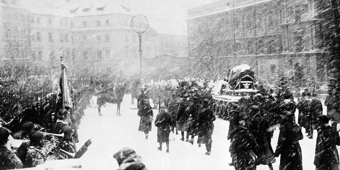 Historische Aufnahme, ein Begräbnis im Schnee, der Sarg wird eskortiert