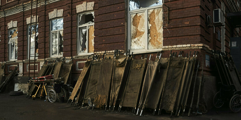 Tragbahren lehnen an die Wand eines Hauses , alle Fensterscheiben sind zersprungen