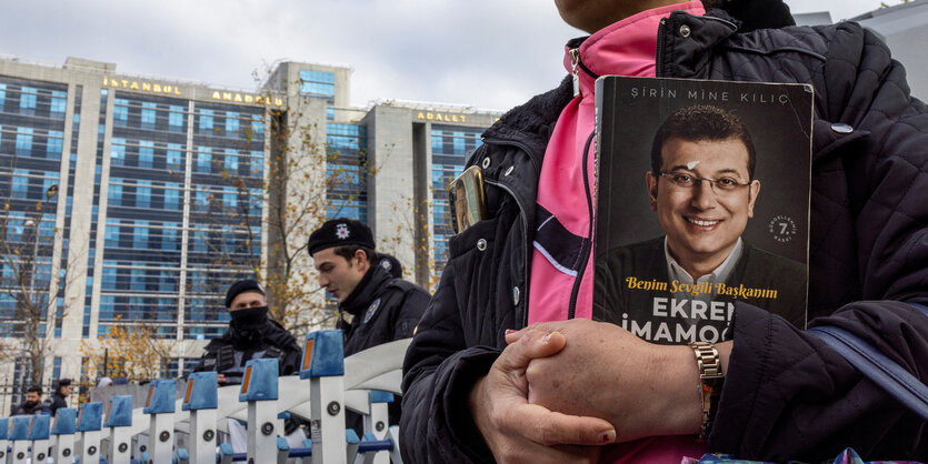 Eine Frau mit einem Buch in der Hand, das Ekrem Imamoglu zeigt