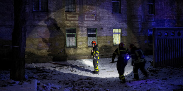 Rettungskräfte leuchten mit einer Taschenlampe ein Gebäude an