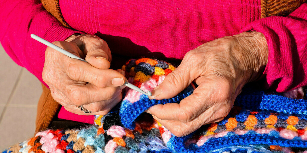 Die Hände einer älteren Person mit Stricknadeln