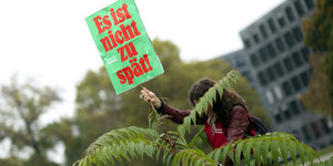 Ein Mensch hält ein Plakat der Initiative für einen Klimaentscheid in die Höhe