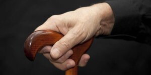 Die Hand eines älteren Menschen am Griff eines Gehstocks