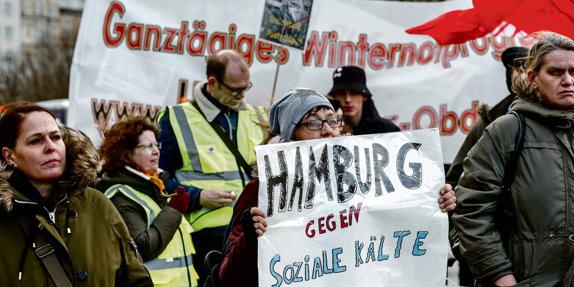 Menschen in dicken Winterjacken halten Protestschilder in den Händen