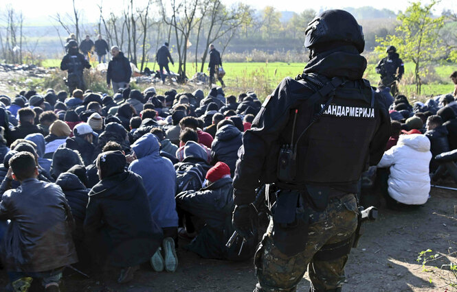 Menschen knieen auf dem Boden, bewacht von Polizisten