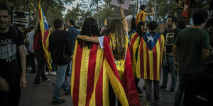 Zwei Frauen sind in eine katalonische und eine spanische Fahne gehüllt und stehen beieinander