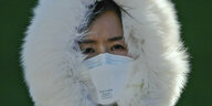 Eine Frau mit Mundschutz und Winterkapuze