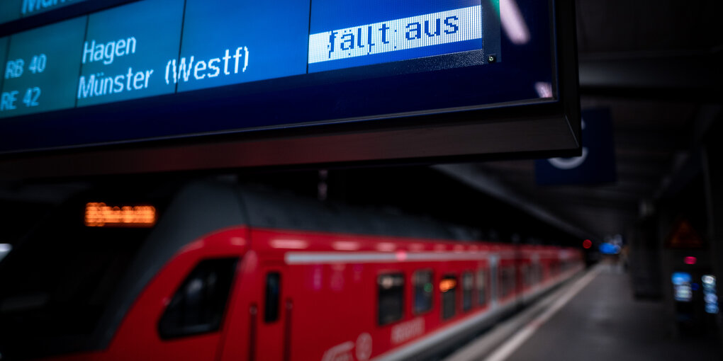 Ein roter Zug steht an einem Bahngleis, auf der Abfahrtsanzeige darüber steht "Zug fällt aus".