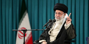 Irans Revolutionsführer Ali Chamenei vor einer Flagge