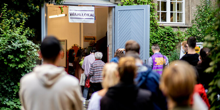 Menschen stehen vor einem Wahllokal Schlange