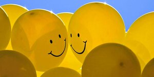Gelbe Luftballons mit Smileys in blauen Himmel
