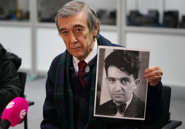 Ein Mann hält eine Fotografie in die Kamera, darauf das Portrait eines Menschen