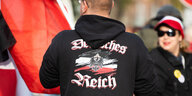 Ein Mann mit einer Kapuzenjacke auf der "Deutsches Reich" steht