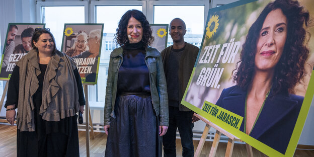 Bettina Jarasch, Susanne Mertens und Philmon Ghirmai stehen vor einem Wahlplakat für Bettina Jarasch