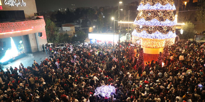 Menschenmenge vor einem erleuchteten Tannenbaum