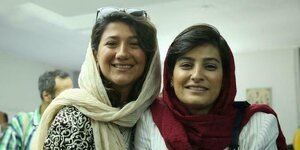 Zwei Frauen mit locker getragenem Kopftuch lächeln in die Kamera