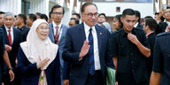 Anwar Ibrahim hebt die Hand zum Gruß, neben ihm seine Frau in einer Gruppe