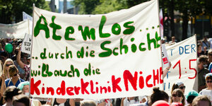 Demonstrationsteilnehmer tragen am 30.06.2015 ein Transparent mit der Aufschrift "Atemlos durch die Schicht will auch die Kinderklinik nicht" auf einer Demonstration der streikenden Pflegekräfte der Charite in Berlin Unter den Linden.