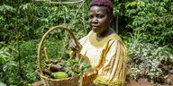 Eine schwarze Frau zeigt einen Korb mit Gemüse