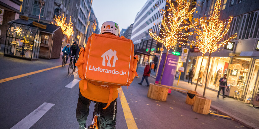 Ein Lieferando-Kurier radelt durch eine weihnachtliche Straße