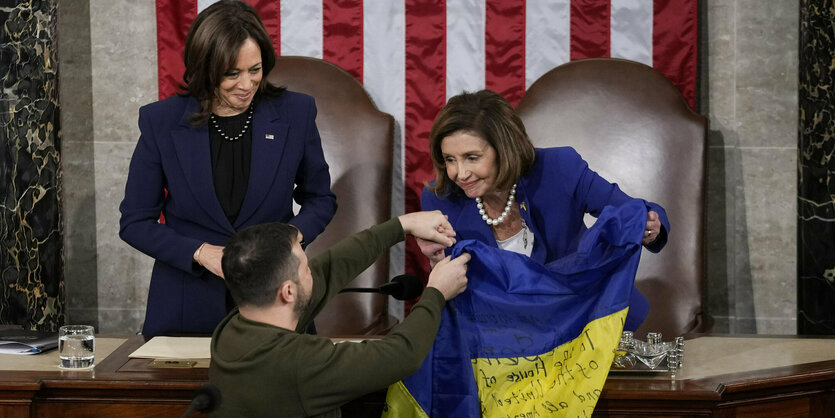 Wolodimir Selenski übergibt am Rednerpult des Repräsentantenhauses eine ukraine Fahne an Nancy Pelosi