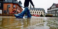 Eine Person geht über den überfluteten Marktplatz von Goslar.