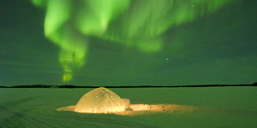 beleuchtetes Iglu und grünes Nordlicht