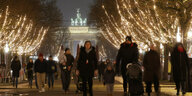 Berlin: Die Weihnachtsbeleuchtung auf der Straße Unter den Linden ist eingeschaltet, während im Hintergrund das beleuchtete Brandenburger Tor zu sehen ist.