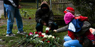 Menschen legen Rosen nieder, um einer 27-Jährigen zu gedenken, die in Lichtenberg umgebracht wurde.