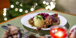 Eine Portion Gänsekeule mit Rotkraut und Klößen steht auf einem Tisch