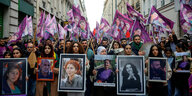 Protestierende mit Konterfeits der Opfer und lila Fahnen