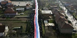 eine superlange serbische Flagge wird durch eine Straße gezogen über hunderte Meter